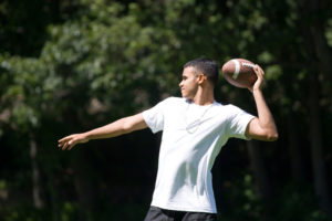 Young high school football player throws a ball during practice. 