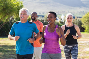 Group of multiracial adult joggers smiling outside.
