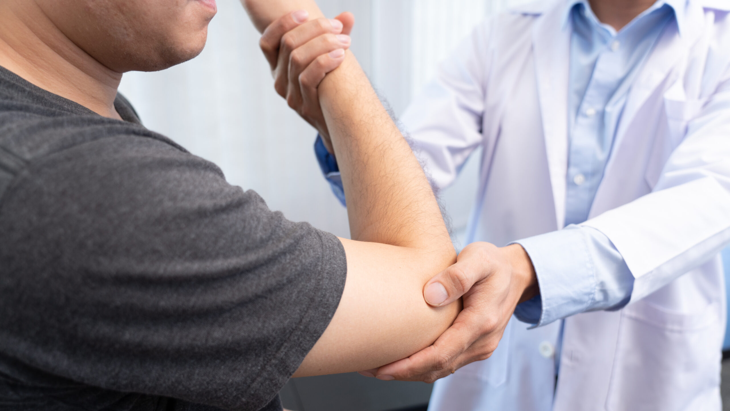 A doctor examines a patient’s elbow. 